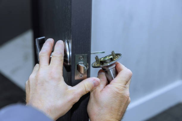 Mechanic installs lock handles on room doors at new house